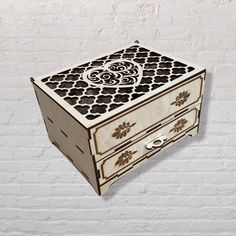 an ornate wooden box with drawers on the side against a white brick wall and floor