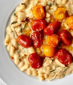 a white plate topped with macaroni and cheese covered in tomatoes