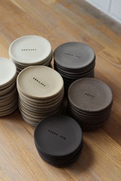 a pile of black and white plates sitting on top of a wooden table next to each other