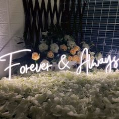 a flower arrangement with flowers and the word forever and always spelled in white neon letters