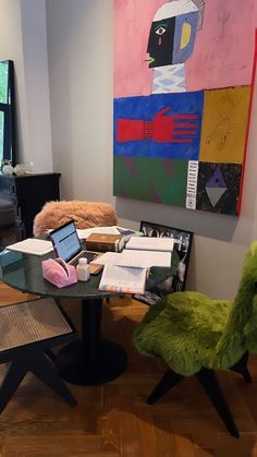 a table with two laptops sitting on it in front of a painting and chair