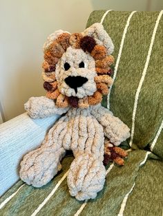 a crocheted stuffed animal sitting on top of a green striped couch cushion with white and brown stripes