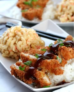 two plates with rice, meat and vegetables on them next to chopsticks in the background