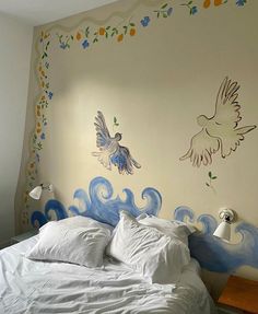 a white bed sitting in a bedroom next to a wall with birds painted on it