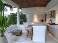 a living room and kitchen area in a house with white walls, floor to ceiling glass windows