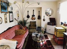 a living room filled with furniture and lots of guitars hanging on the wall above it