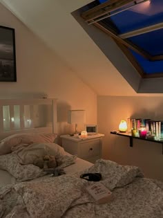 a bedroom with a skylight above the bed and some books on the nightstands