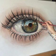 someone is drawing an eye with colored pencils on the paper and it looks like they have long eyelashes