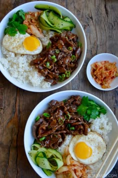 two bowls filled with rice, meat and veggies on top of a wooden table