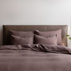 a bed with two pillows and some plants on the headboard in front of it