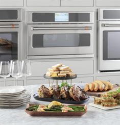 a kitchen counter topped with plates and trays filled with food next to an oven