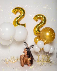 a woman sitting in front of balloons and confetti