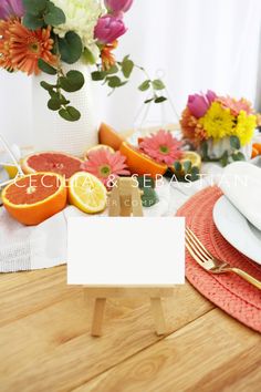 a table set with place cards, plates and flowers