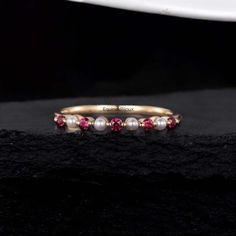 a gold ring with pearls and garnets on the side, sitting on a black surface