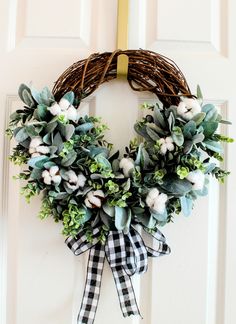 a wreath hanging on the front door with cotton balls and greenery around it,