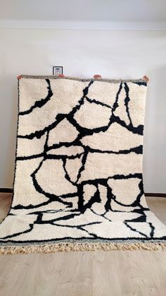 a black and white rug on the floor in front of a wall with a frame