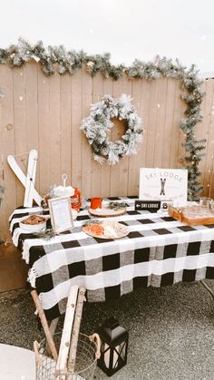 an outdoor picnic table set up with food and decorations for the holiday season in front of a wooden fence