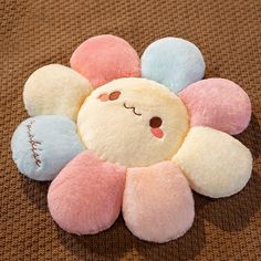 a small stuffed animal with four balls in the shape of a flower on a brown surface