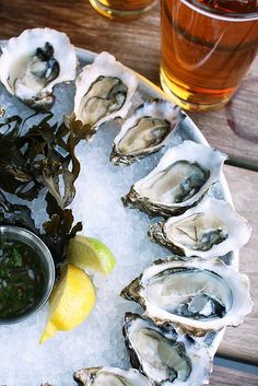 oysters on an ice tray with lemon wedges and beer