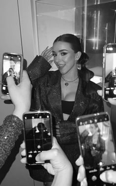 a woman taking a selfie with her cell phone and two other people holding up their phones