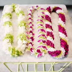 three flower leis laid out on top of a marble table with the letters u and u spelled by them