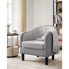 a living room with a gray chair and bookshelf