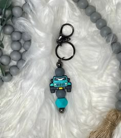 a keychain with a blue car on it sitting next to beads and other items