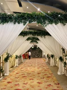 an aisle decorated with greenery and white draping for a wedding or reception