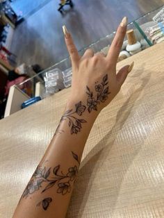 a woman's hand with a flower tattoo on her left arm and the middle finger