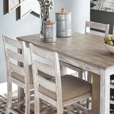 a wooden table with two chairs and a bowl of fruit on top of the table