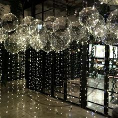 some shiny balls hanging from the ceiling in front of a mirror with lights on it