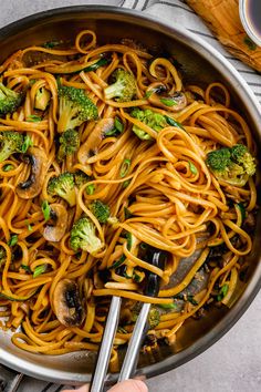 a pan filled with noodles, broccoli and mushrooms