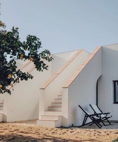 two chairs are sitting in front of a white building with stairs leading up to it