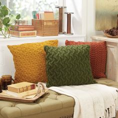 a living room filled with lots of pillows and blankets on top of a couch next to a window