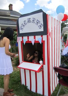 a woman standing next to a carnival booth