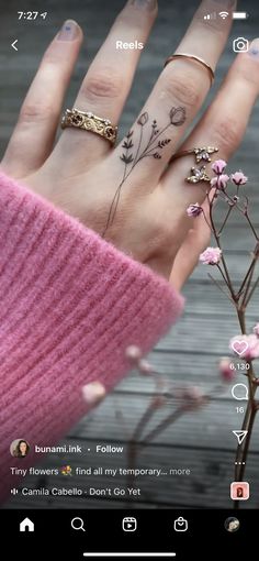 a person's hand with tattoos on it and flowers growing out of the palm