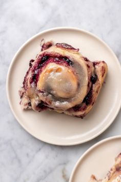 two white plates topped with pastries on top of a marble countertop next to each other