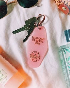 a pink keychain sitting on top of a white towel next to sunglasses and other items