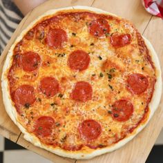 a pepperoni pizza sitting on top of a wooden table