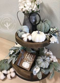 a three tiered tray with pumpkins, cotton balls and other fall decorations on it