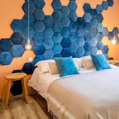 a bed with blue hexagonal tiles on the headboard and pillows in front of it