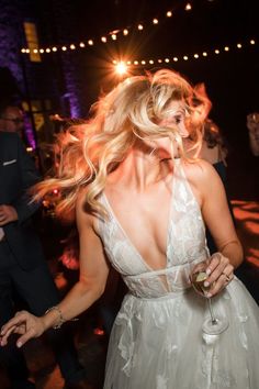 a woman in a white dress dancing at a party with her hair blowing in the wind