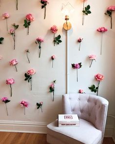 a white chair sitting in front of a wall with pink flowers on it