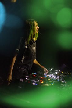 a woman with green hair is djing in the dark