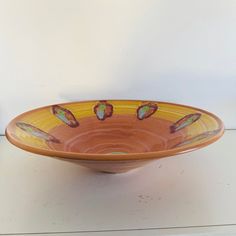 an orange bowl sitting on top of a white table