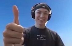 a young man wearing headphones gives the thumbs up sign