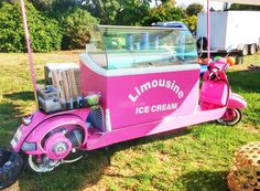 a pink ice cream cart parked in the grass