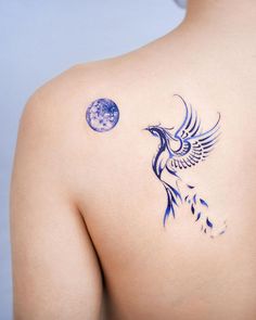 the back of a woman's shoulder with a blue bird and moon tattoo on it