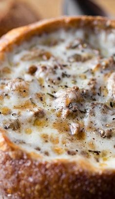 a close up of a bread bowl with cheese and meat