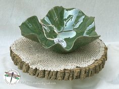 a green bowl sitting on top of a piece of burlock next to a white table cloth